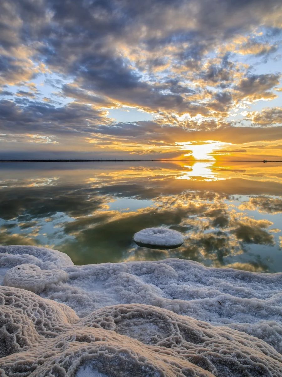 Chaka Salt Lake at sunset, featuring crystal clear waters and unique salt formations reflecting the colorful sky.