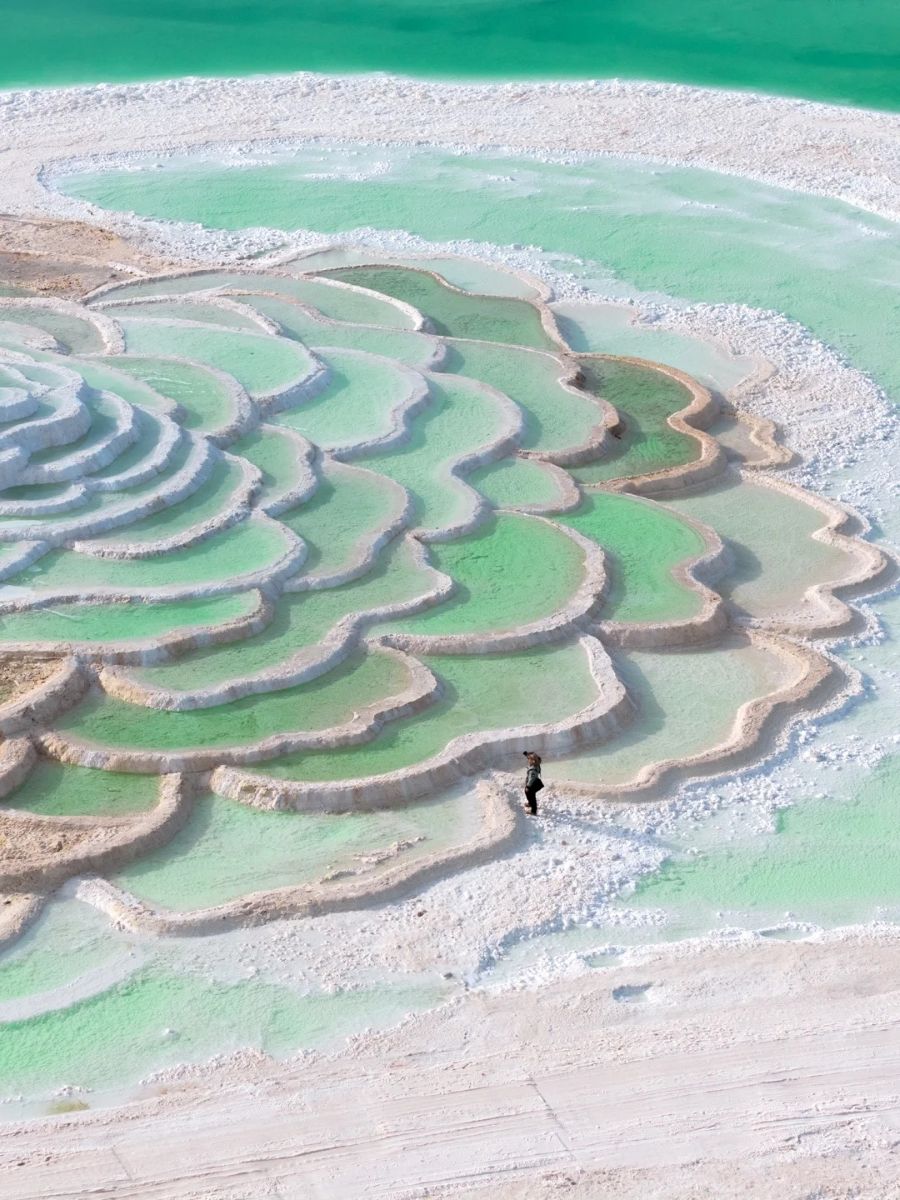 Chaka Salt Lake's stunning layered salt formations in vibrant shades of green and turquoise, seen from above.