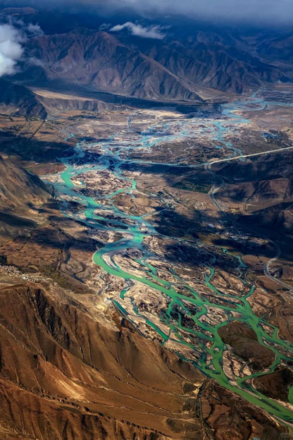 Aerial view of vibrant rivers winding through mountainous landscape in Gansu and Qinghai, China.
